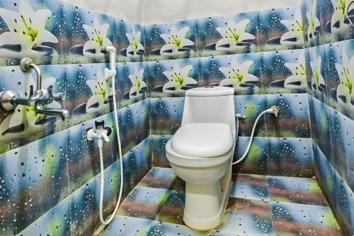 a bathroom with a toilet and a mural of flowers at Hotel Qness in Hyderabad