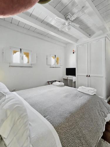 a white bedroom with a large bed and a television at La Via della Giudecca in Syracuse