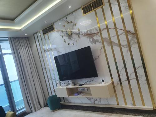 a living room with a tv on a wall at Stylish 2 BR Apartment in Ajman Residences Tower 4 in Ajman 