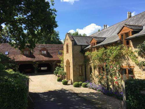 an old stone house with a driveway and flowers at Wooden Cabbage Barn in Dorchester