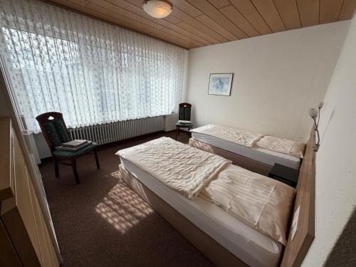 a bedroom with two beds and a chair and a window at Hotel Restaurant Zum Schwan in Goch
