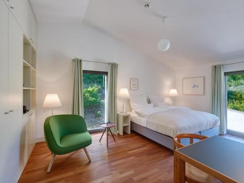a bedroom with a bed and a green chair at Gästehaus Cantzheim in Kanzem