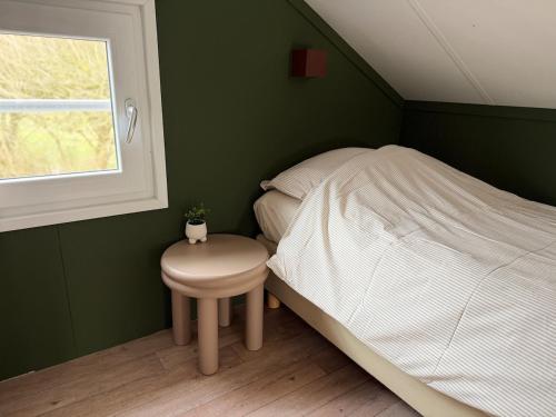 a bedroom with a bed and a table and a window at De Meerkoet Tiny House Tussen de Dijken in Driewegen