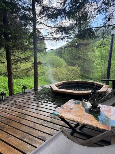 a wooden deck with a boat in the woods at Шале Ротило in Krivopolʼye