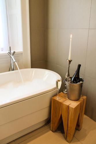 a bath tub with a candle and two bottles of wine at Tigerlily in Edinburgh