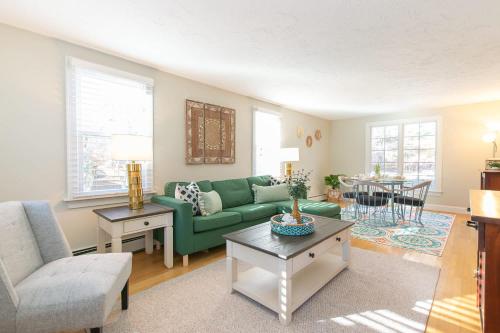 a living room with a green couch and a table at Spacious Stone Fire Pit Game Room in Barnstable