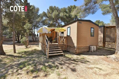 a tiny house with a porch and an umbrella at Lou Soleil - Bungalow - 6 couchages in Carry-le-Rouet