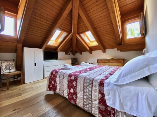 a bedroom with a bed in a room with wooden ceilings at Mansarda vista lago in Auronzo di Cadore