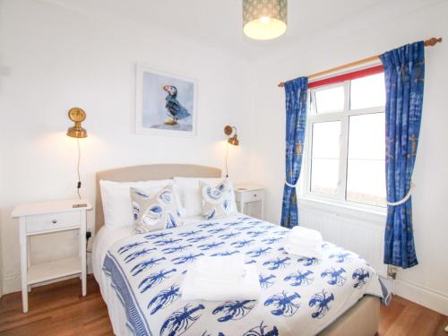 a bedroom with a blue and white bed and a window at 4 The Elms in Salcombe