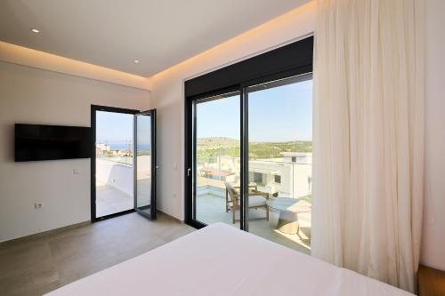 a bedroom with a bed and a large window at POLYTELIA - Luxury Living in Elaía