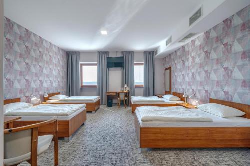 a room with four beds and a table and a desk at Hotel Aviator - kompleks Silesia Ring in Kamień Śląski