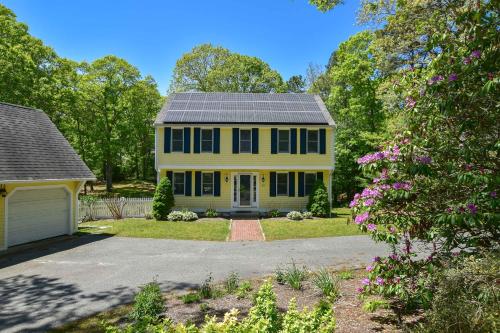 a yellow house with a solar roof at Spacious Stone Fire Pit Game Room in Barnstable