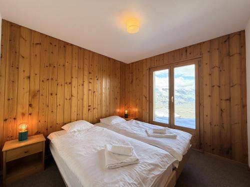 a bedroom with a large bed and a window at Fontannets 001 COSY & MOUNTAIN chalet 10 pers in Veysonnaz