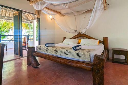 a bedroom with a bed with a canopy at Kusini Beach Cottages in Diani Beach