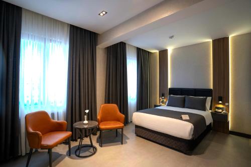 a hotel room with a bed and two chairs at Kucuk Velic Hotel in Gaziantep