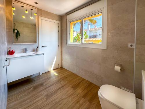 a bathroom with a toilet and a sink and a window at Villa Rocamar by Hello Homes Sitges in Sitges