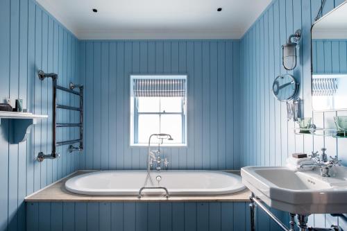 a blue bathroom with a tub and a sink at The Swan Hotel in Southwold