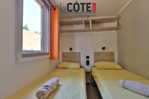 two beds in a room with a coffee sign on the wall at Bleu Paradou - Bungalow - 6 couchages in Carry-le-Rouet