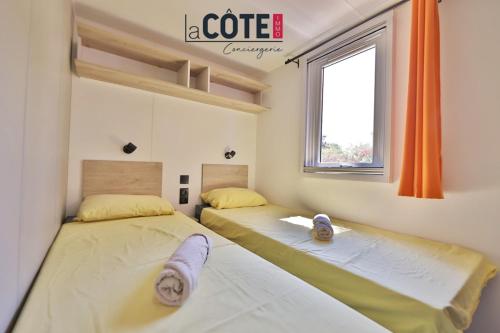 two beds in a room with a window at Bleu Paradou - Bungalow - 6 couchages in Carry-le-Rouet