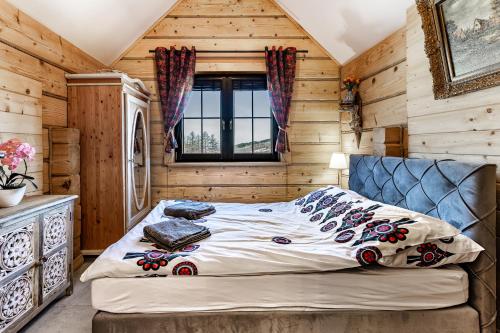 a bedroom with a bed in a room with wooden walls at Villa Ligęzówka in Chyrowa