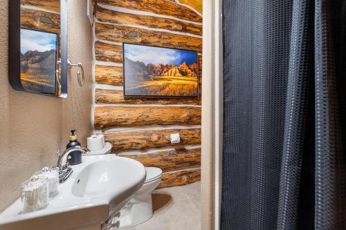 a bathroom with a sink and a toilet with a log wall at Pinecrest Cabin- Serene Black Hills Getaway in Rapid City