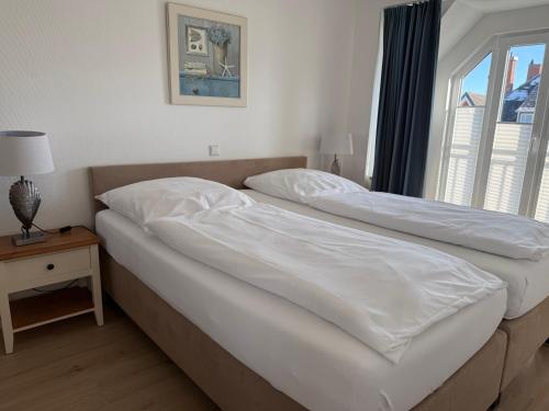 two beds in a bedroom with a window at Appartementhaus Hoppe in Sylt