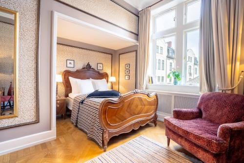 a bedroom with a bed and a chair and a window at Grand Hotel Lund in Lund