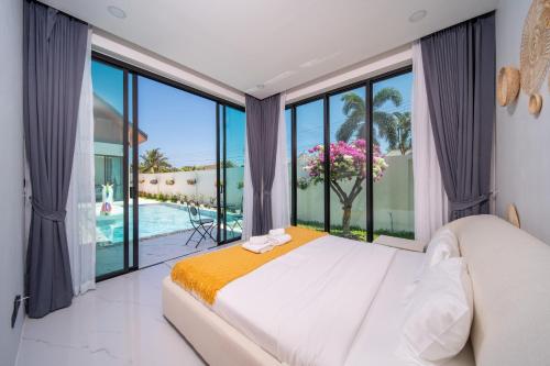 a bedroom with a white bed and large windows at Yuan Villa VIP in Rawai Beach