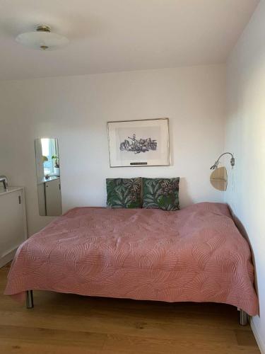 a bedroom with a large bed with a pink comforter at Nära strand och hav in Halmstad