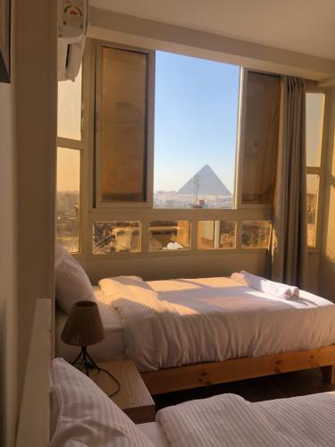 a bedroom with two beds and a window with a pyramid at Rafifi pyramids inn view in Cairo