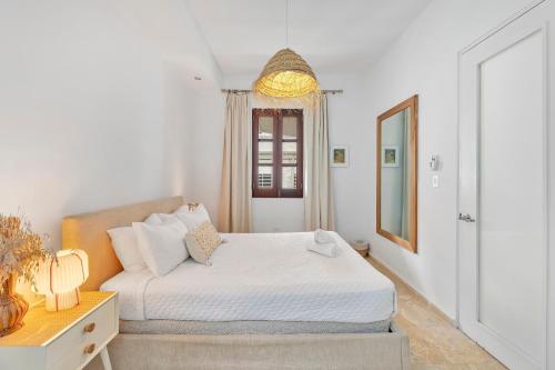 a white bedroom with a bed and a mirror at Boho Oasis by the Beach in San Juan