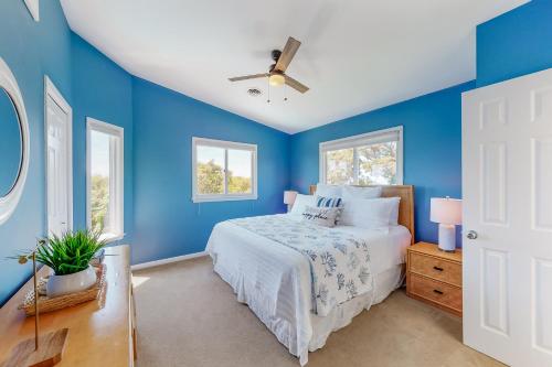 a blue bedroom with a bed and a ceiling fan at Dock Holiday OBX Village in Duck