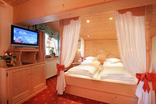 a bedroom with a bed with curtains and a television at Pension Sunnberg in Going