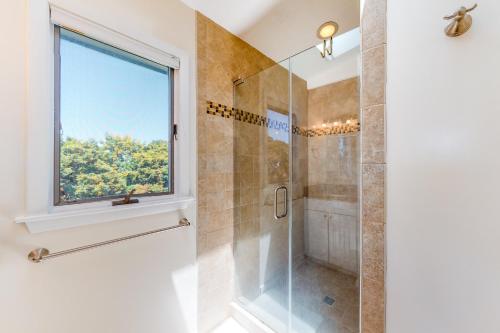a bathroom with a shower and a window at Dock Holiday OBX Village in Duck
