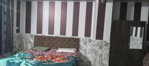 a bedroom with a bed and a striped wall at Astha Restorent & Geust House in Aonla