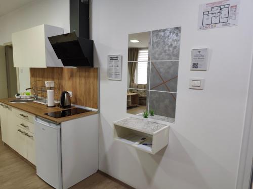 a white kitchen with a sink and a refrigerator at Six Windows Apartmani in Bačka Topola