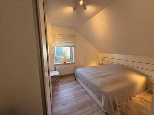 a small bedroom with a bed and a window at Vollmöbliertes Apartment am Deich in Neuendeich