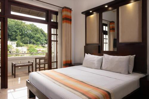 a bedroom with a bed and a large window at Oak Ray Serene Garden Hotel in Kandy