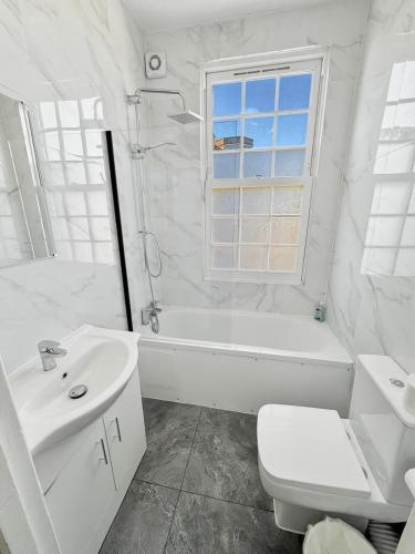 a white bathroom with a tub and a toilet and a sink at London Duo & Quad Rooms in Zone 2 - Willesden Green in London