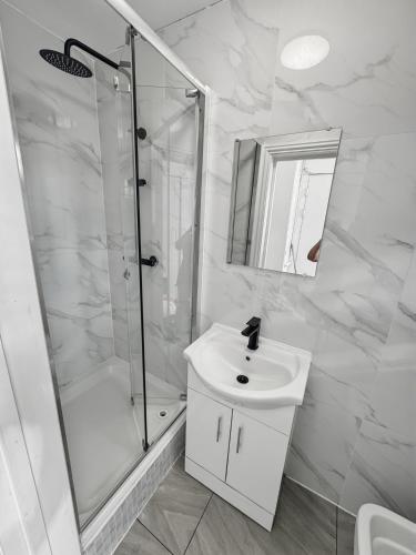a white bathroom with a shower and a sink at London Duo & Quad Rooms in Zone 2 - Willesden Green in London
