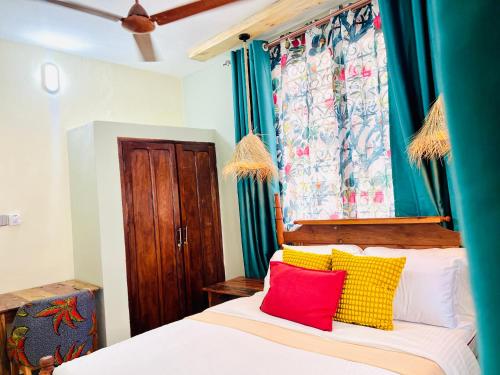 a bedroom with a bed with red and yellow pillows at Nuru House Stone Town Ensuite 3BR Apartment in Zanzibar City