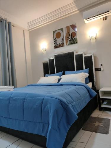 a bedroom with a bed with a blue comforter at Nguem's Appart in Odza I