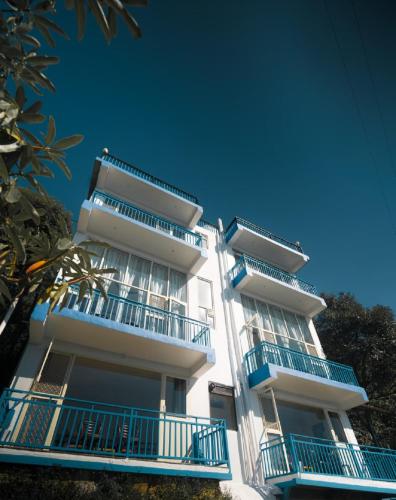 a tall white building with blue balconies on it at Mountain Golden Ray in Mukteshwar