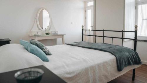 ein Schlafzimmer mit einem Bett mit blauen Kissen und einem Spiegel in der Unterkunft Casas do Vale - T1 in Nordeste