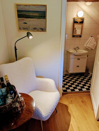 a living room with a chair and a table and a sink at Farmors Lycka in Kivik