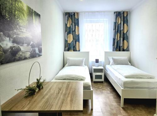 a bedroom with two beds and a wooden table at Leinstraße Ferienwohnung Neustadt in Neustadt am Rübenberge