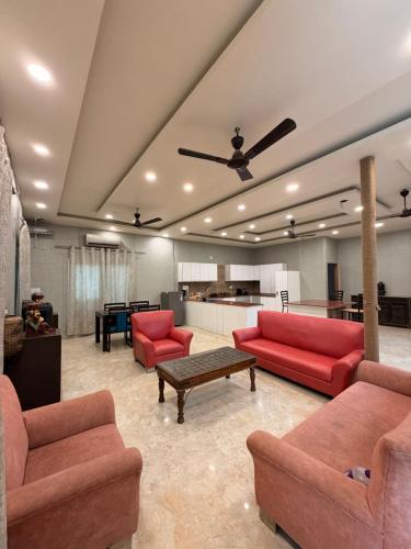 a large living room with red couches and a table at The Machan Farmhouse in Noida