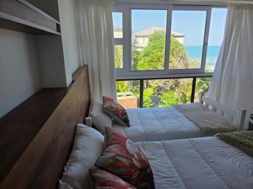 a bedroom with two beds and a large window at Hartsepunt Seesig in Hartenbos