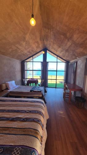 two beds in a room with a large window at Casa de Primo in Puno