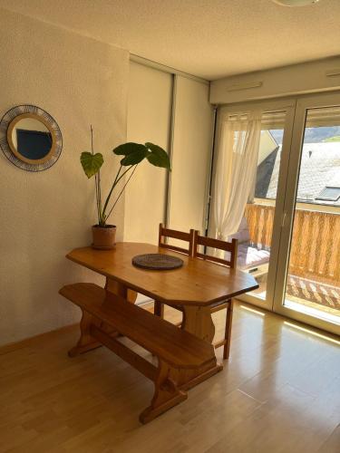 a dining room table with a potted plant and a bench at Charmant appartement avec vue montagne in Luz-Saint-Sauveur